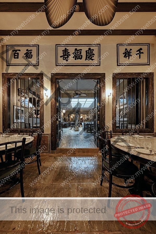 A warm shophouse interior with timber flooring and dining tables